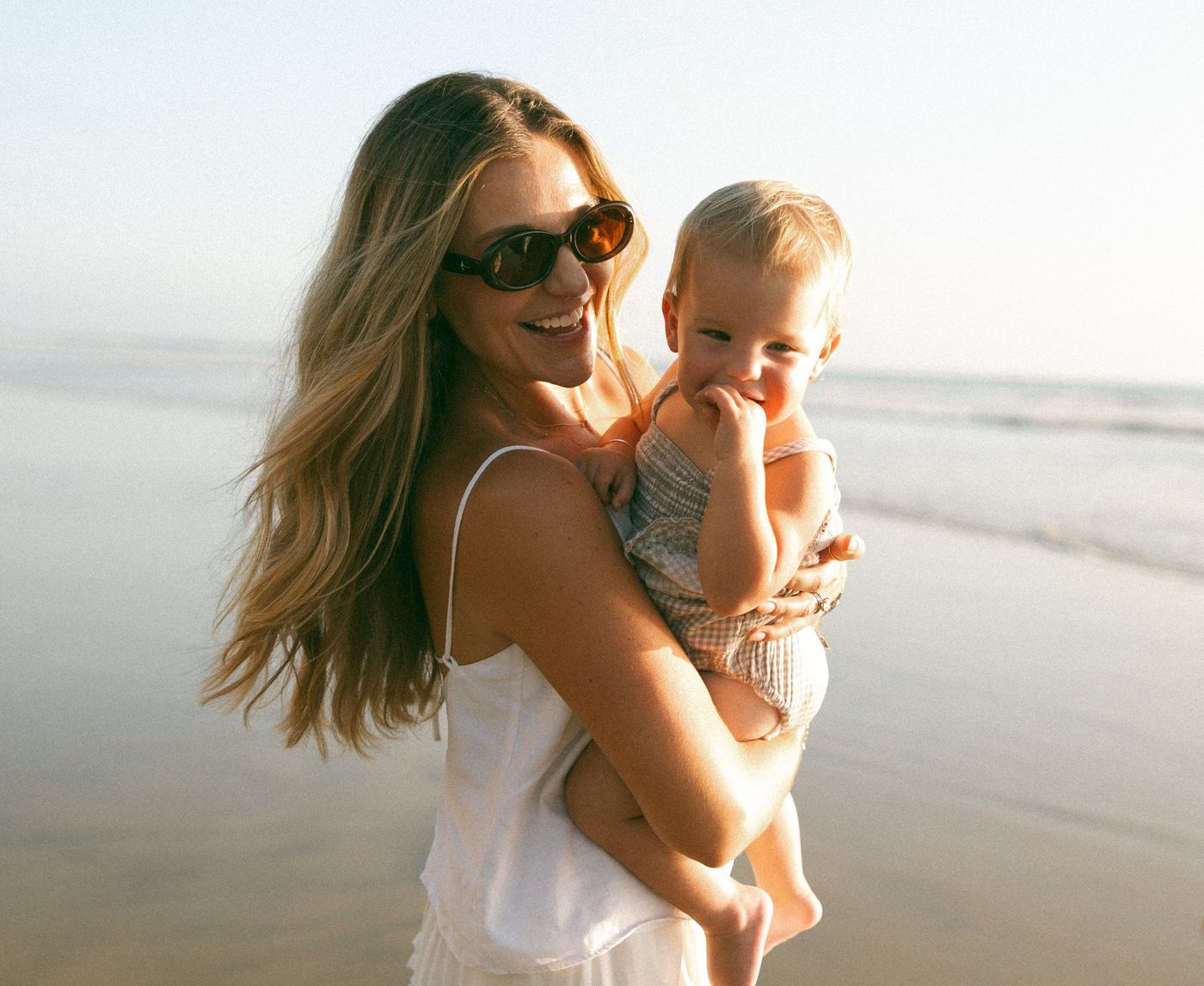Alexa smiling with her toddler on the beach